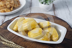 Ripe jackfruit fruits served on white long plate on wooden board