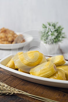 Ripe jackfruit fruits served on white long plate on wooden board