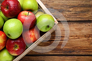 Ripe juicy apples in wooden crate on table, top view. Space for text