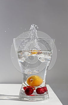 Juicy ripe fruit red cherries float in a glass vessel in clear transparent water with air bubbles