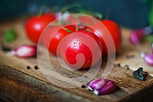 Ripe juicy beautiful tomatoes with water drops on a dark background close-up. Natural texture of vegetables and greens, parsley, o