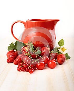 Ripe juicy berries and jug on the table