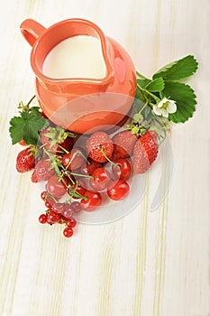 Ripe juicy berries and jug on the table