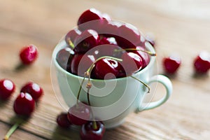 Ripe juicy cherries in Cup on wooden background