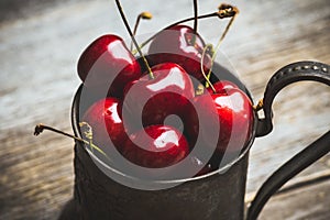 Ripe and juicy cherries in old metal cup on the dark rustic background