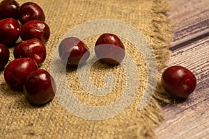 Ripe juicy cherries scattered on a homespun fabric with a rough texture. Close up