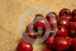 Ripe juicy cherries scattered on a homespun fabric with a rough texture. Close up