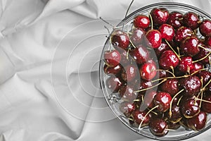Ripe juicy cherry covered with droplets of water in a transparent bowl