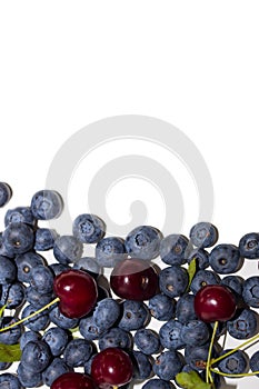 Ripe and juicy fresh pickedblueberries and cherries isolated on white background, close up. Copy space.