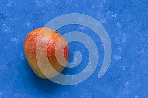 Ripe juicy fruit of the Brazilian mango from the tropics on a blue background with place for text. Exotic fresh fruits