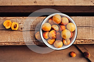 Ripe juicy homemade apricots with cracks and flaws in the plate and scattered on wooden boards, top view