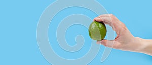 Ripe juicy lime in hand isolated on blue background. Healthy eating and dieting concept