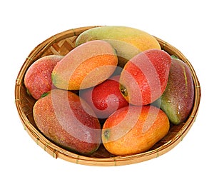 Ripe juicy mangoes in a round bamboo tray
