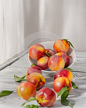 Ripe juicy peaches lie in a plate on a wooden table.