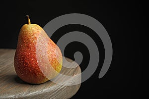Ripe juicy pear on brown wooden table against background. Space for text