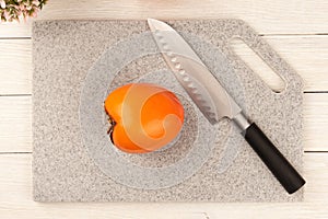 Ripe, juicy persimmon on a cutting board made of artificial stone