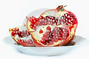 Ripe juicy pomegranate fruit (Punica granatum) in a white plate isolated on white background