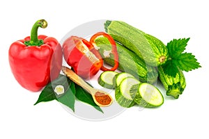 Ripe juicy red sweet bell peppers, paprika, green zucchini with flower, spice on wooden spoon and leaves. Isolated on white
