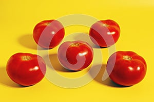 Ripe juicy red tomatoes on yellow background