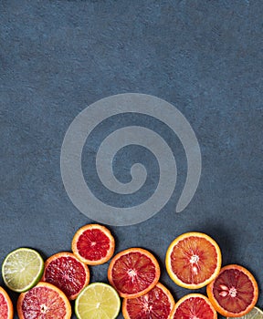 Ripe juicy slices of red oranges spread out on a gray blue background