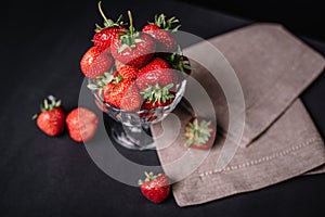 Ripe juicy strawberries in a glass on a dark background