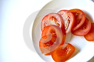 Ripe and juicy tomatoes sliced on a white plate