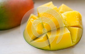 Ripe juicy yellow exotic mango cut into cubes on wooden background. Tropical delicacy full of vitamins for a healthy