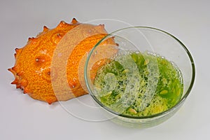 A ripe Kiwano or Horned Melon fruit with green jelly-like flesh scooped out in a small glass bowl