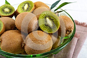 Ripe kiwi fruit in a bowl on a white wooden background.