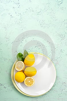 Ripe lemons on a plate on a mint-colored table. Flatt-barking.