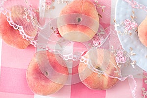 Ripe light pink peaches spread out on the tablecloth. Sweet peach fruit background