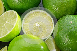 Ripe lime fruits with slices and lime leaves on a gray stone table