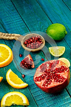 Ripe lime, orange, pomegranate fruit on wooden vintage background.