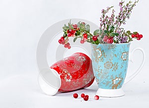 Ripe lingonberries and varicolored cups with ornament