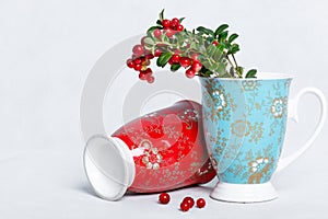 Ripe lingonberries and varicolored cups with ornament