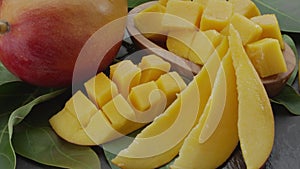 Ripe mango fruits with slices and mango leaves slowly move in the frame.