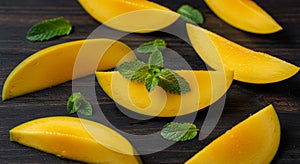 Ripe Mango Slices with Fresh Mint on Dark Wooden Background