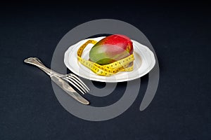 Ripe mango in a white plate wrapped with a tape measure