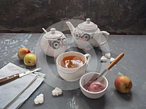 Ripe nectarines in a ceramic bowl, cutlery, tea mug