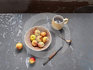 Ripe nectarines in a ceramic bowl, cutlery, tea mug