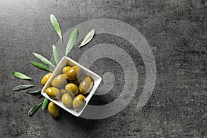 Ripe olives covered with oil in dish and leaves