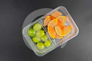 Ripe orange and green grapes in a takeaway plastic box