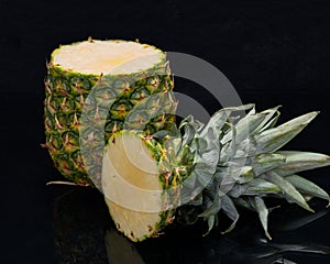 Ripe Organic Pineapple isolated on a black mirror background. Ananas comosus from Bromeliaceae family