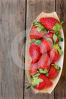 Ripe organic strawberries in birchbark bowl on dark wood background, top view, summer, healthy food photo