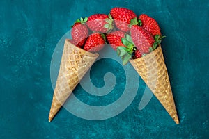 Ripe organic strawberries in waffle ice cream cones, pouring imitation, dark blue background