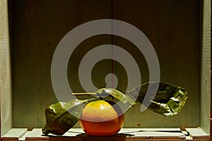 Ripe organic tangerines with leaves in wooden box in bright sunlight with copy space. Natural tropical fruit concept image