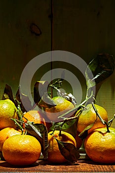 Ripe organic tangerines with leaves in wooden box in bright sunlight with copy space. Natural tropical fruit concept image