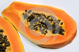 ripe papaya fruit cut in half with seeds isolated on white background.