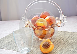 Ripe peaches and glass of juice on a table, cut peach, of a beautiful vase in the shape of a basket background.