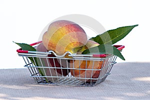 Ripe peaches and green leaves in a metal basket